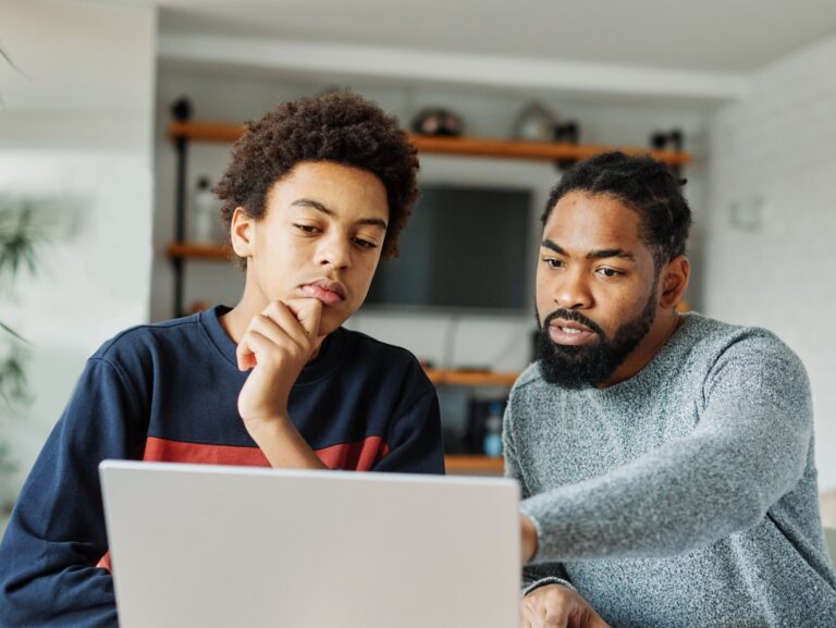 Father and son doing homework with laptop