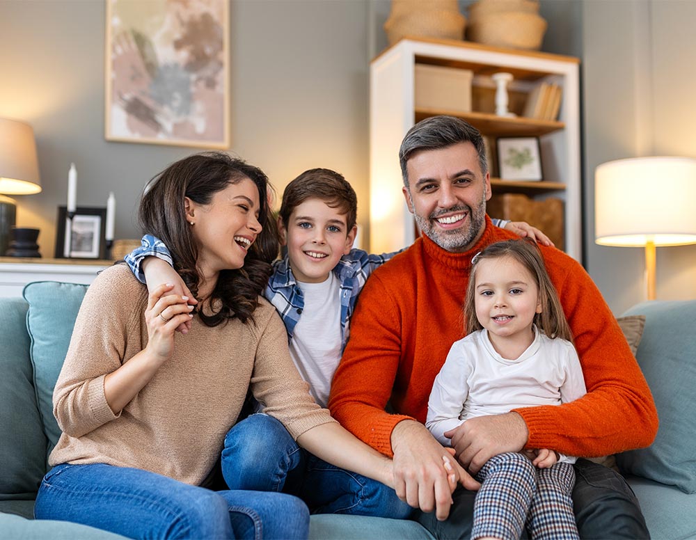 Happy family having fun at home, parents and little children sit on sofa together