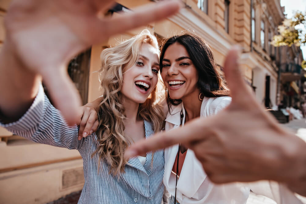 Laughing blithesome woman with dark hair walking down the street with friend