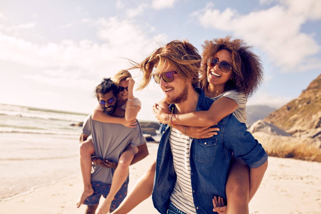 Two happy young men giving their girlfriends piggyback rides