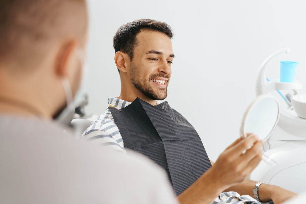 Male Dentist discussing with happy patient after treatment