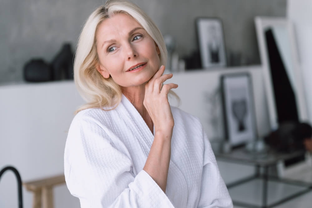 Head shot portrait of calm middle aged woman touching her perfect smooth face
