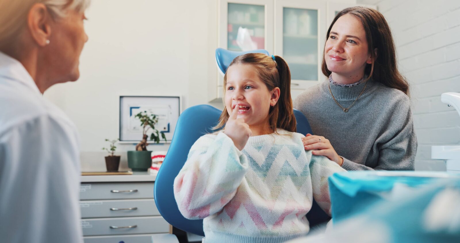 Child, dentist and show tooth at dental consultation with orthodontist for advice or cleaning