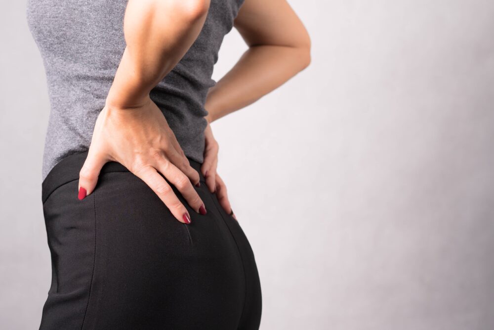 Osteoporosis Day Closeup of woman's hands touching her lower back to reduce the pain