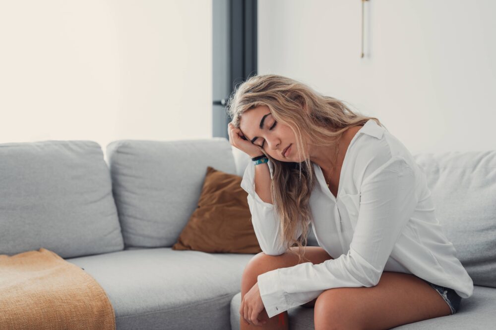 Depressed or tired teen girl feeling stress headache hurt pain sitting alone at home