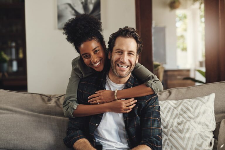 Happy Couple Sitting On Couch At Home