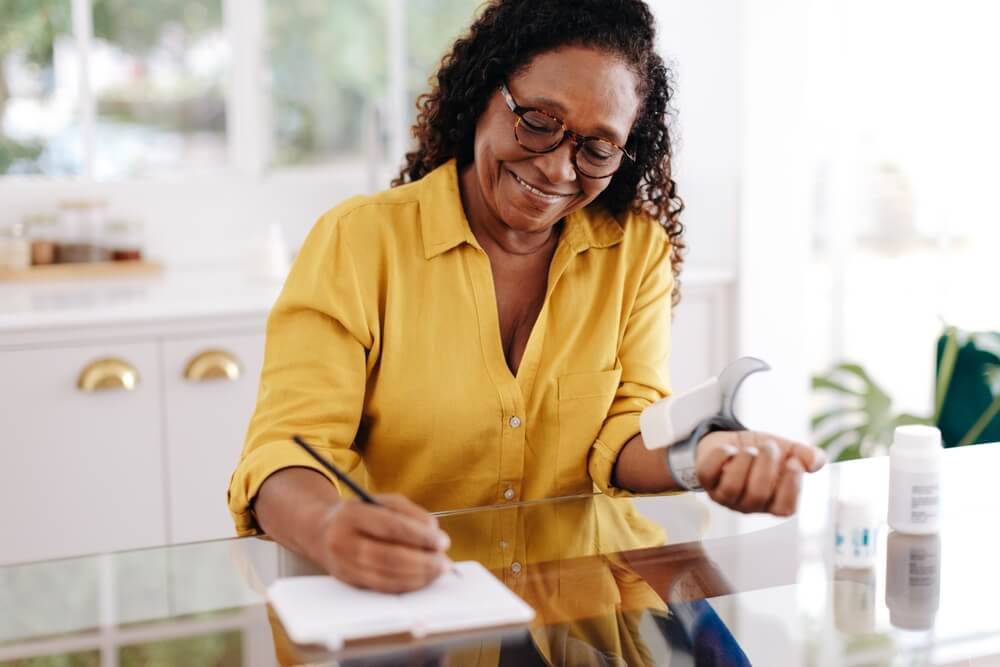 Happy woman using a home blood pressure monitor to manage her health