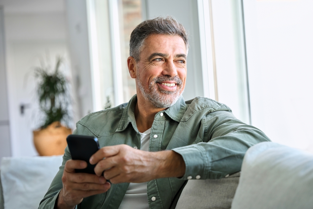 Happy older mature middle aged man holding mobile phone