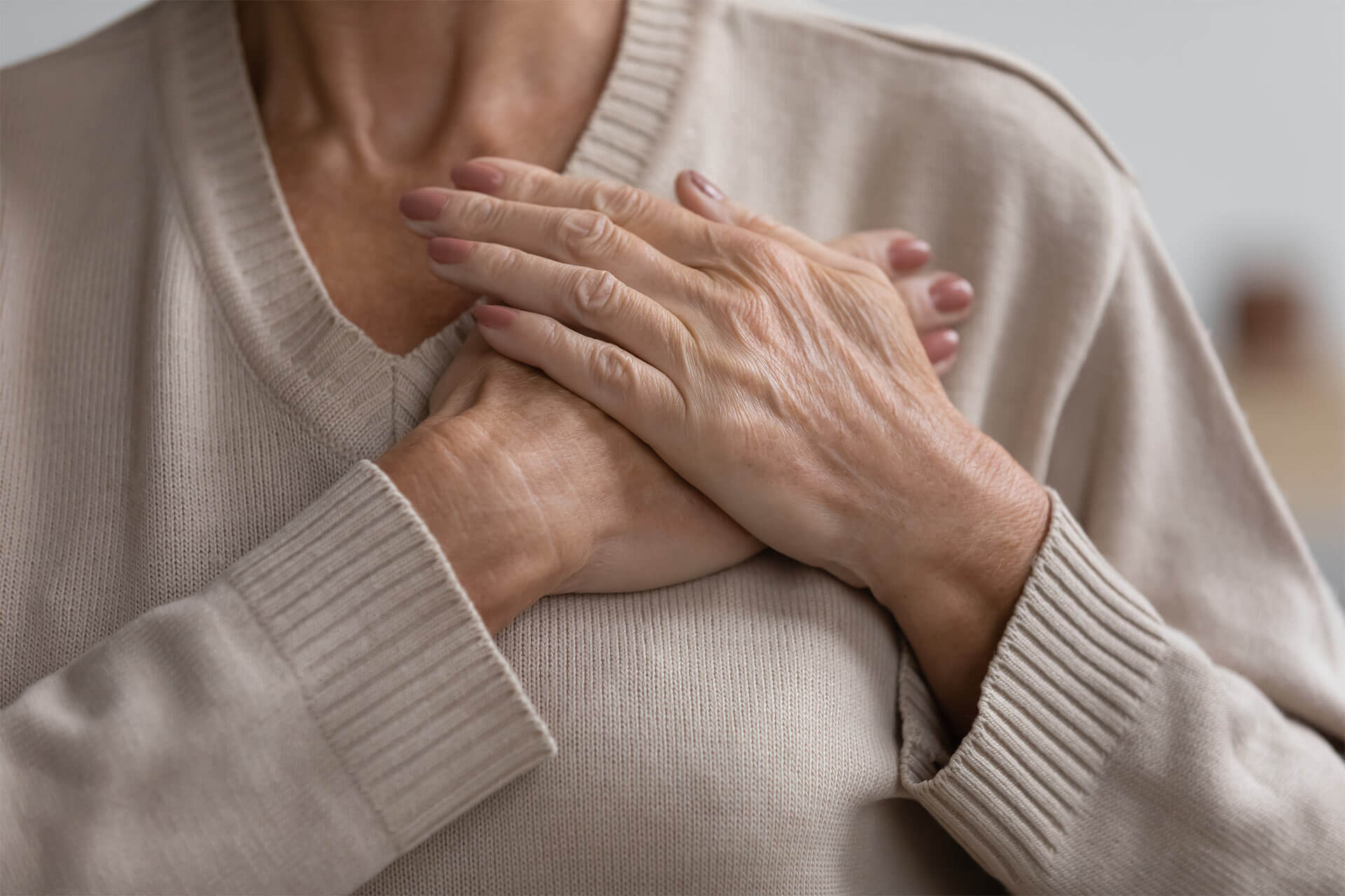 Close up cropped image hopeful grateful mature senior woman keeping hands on chest