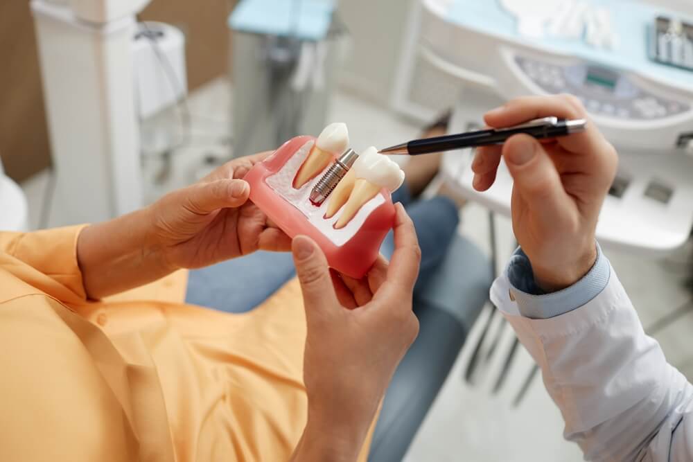 senior woman holding tooth model during consultation