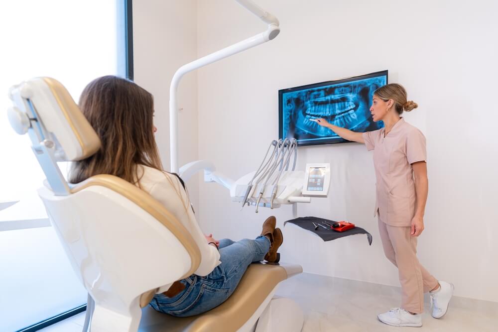 Dentist showing x-ray on monitor to young client