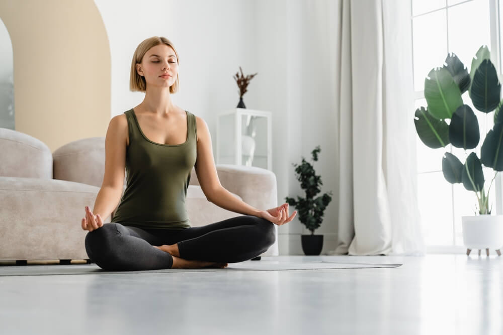Relaxed young woman doing yoga in sitting position at home