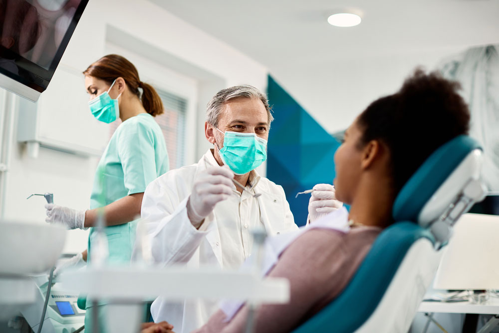 Smiling dentist communicating with woman while checking her teeth
