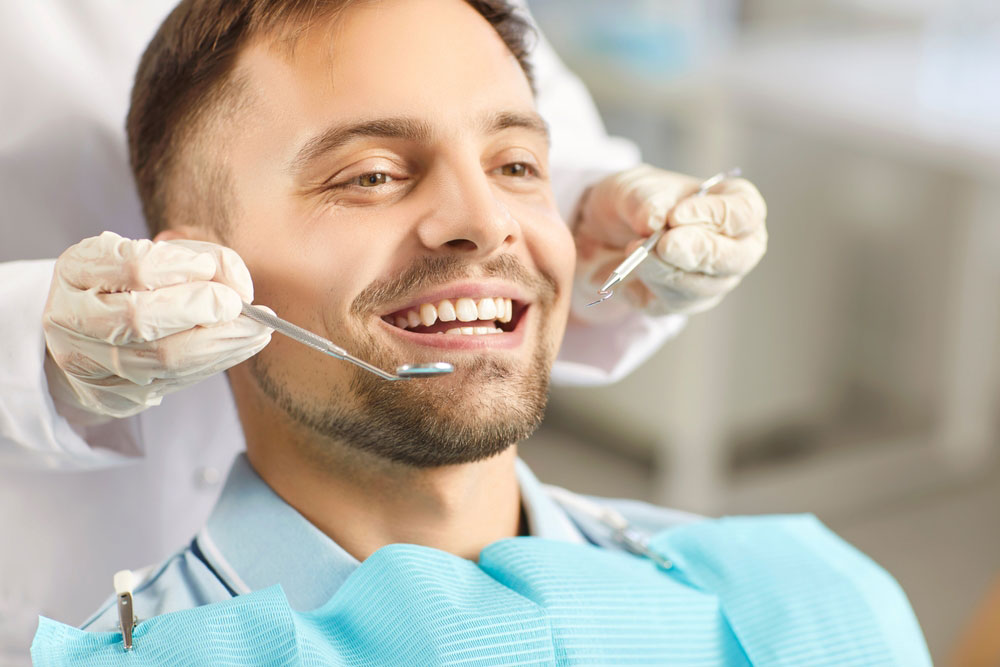 dentist performing a dental exam on a man patient during a clinic visit