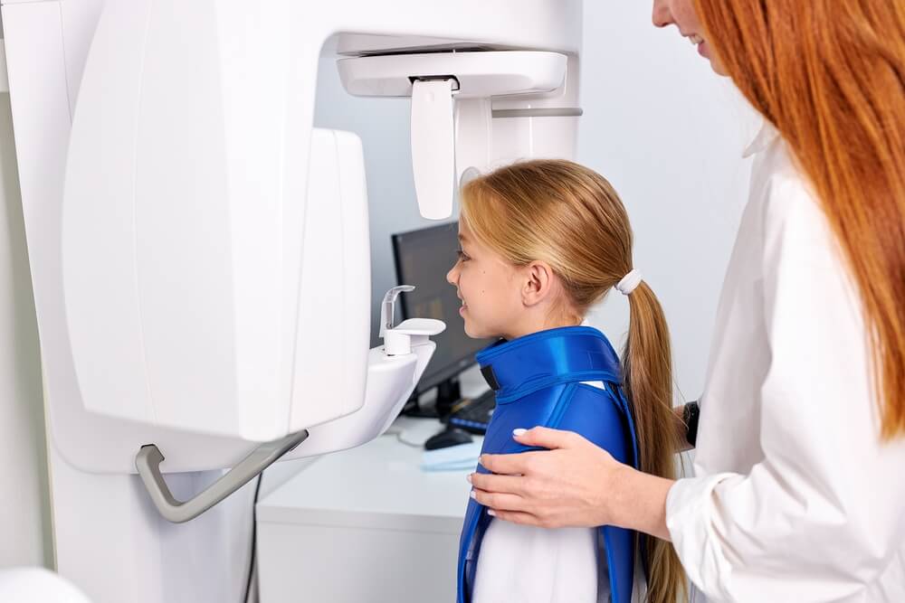 Woman dentist taking teeth x-ray of beautiful child