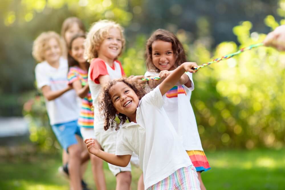 Kids play tug of war in sunny park