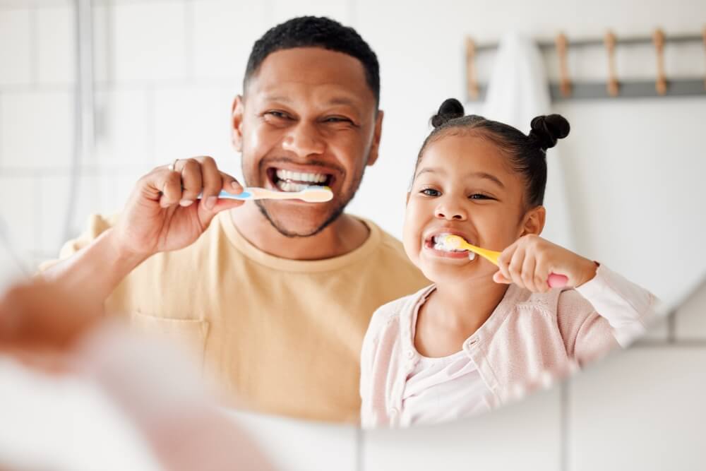 Child and dad brushing teeth