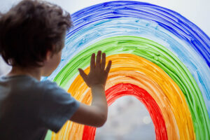 child at home draws a rainbow on the window