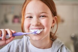 pretty child cleaning her teeth in diligent way