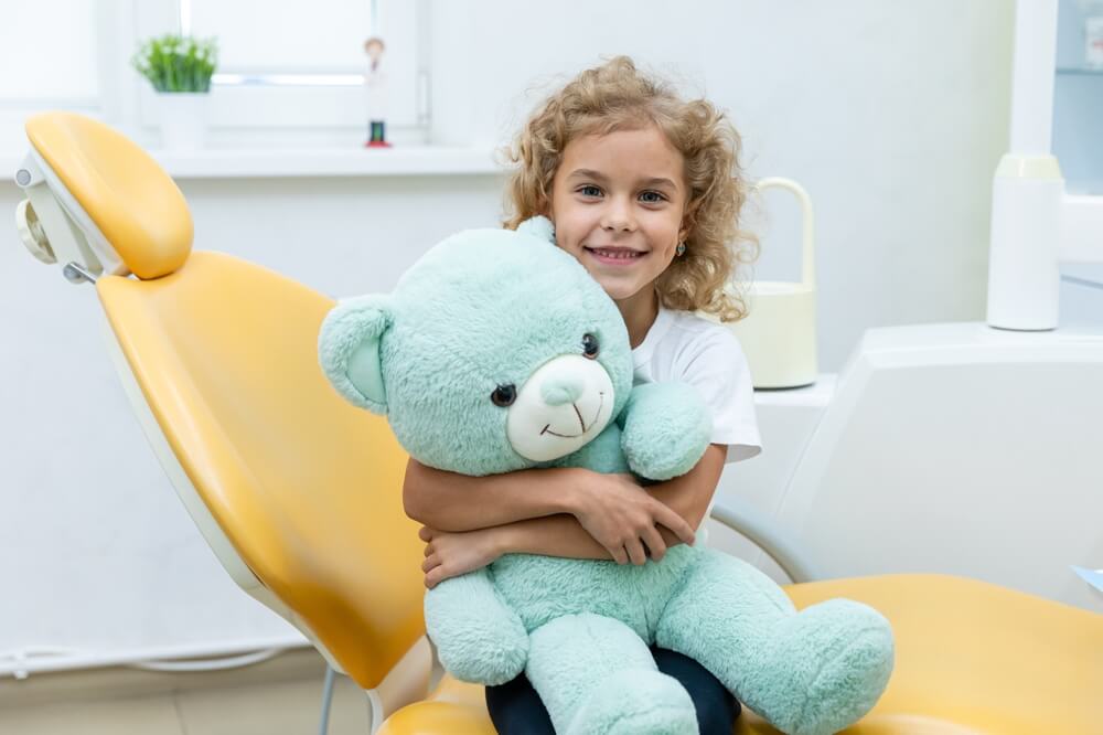 Happy little girl having dentist's appointment in modern clinic