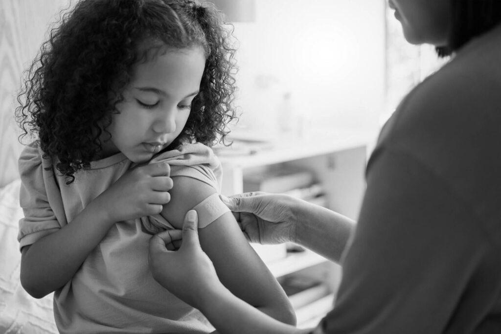 Covid nurse vaccinating child putting a bandage on at a clinic