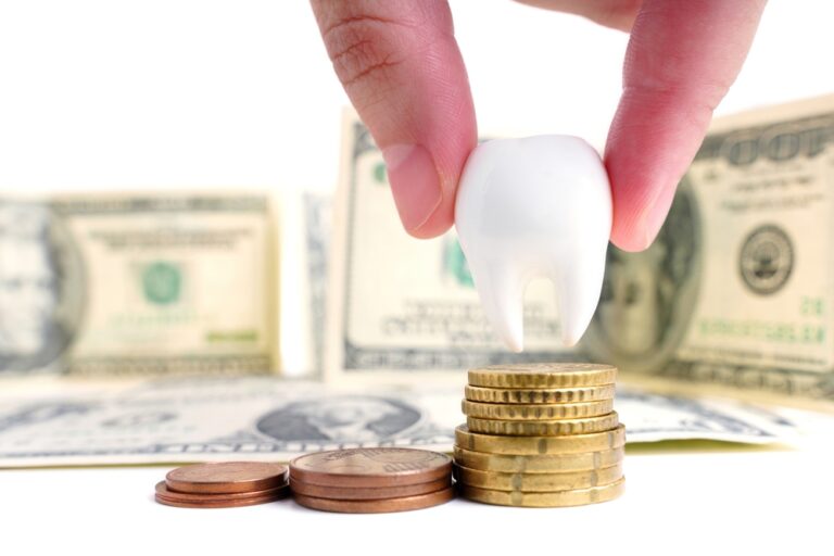 Pinch-holding,A,Large,White,Tooth,Above,Coin,Stacks,Against,Dollar