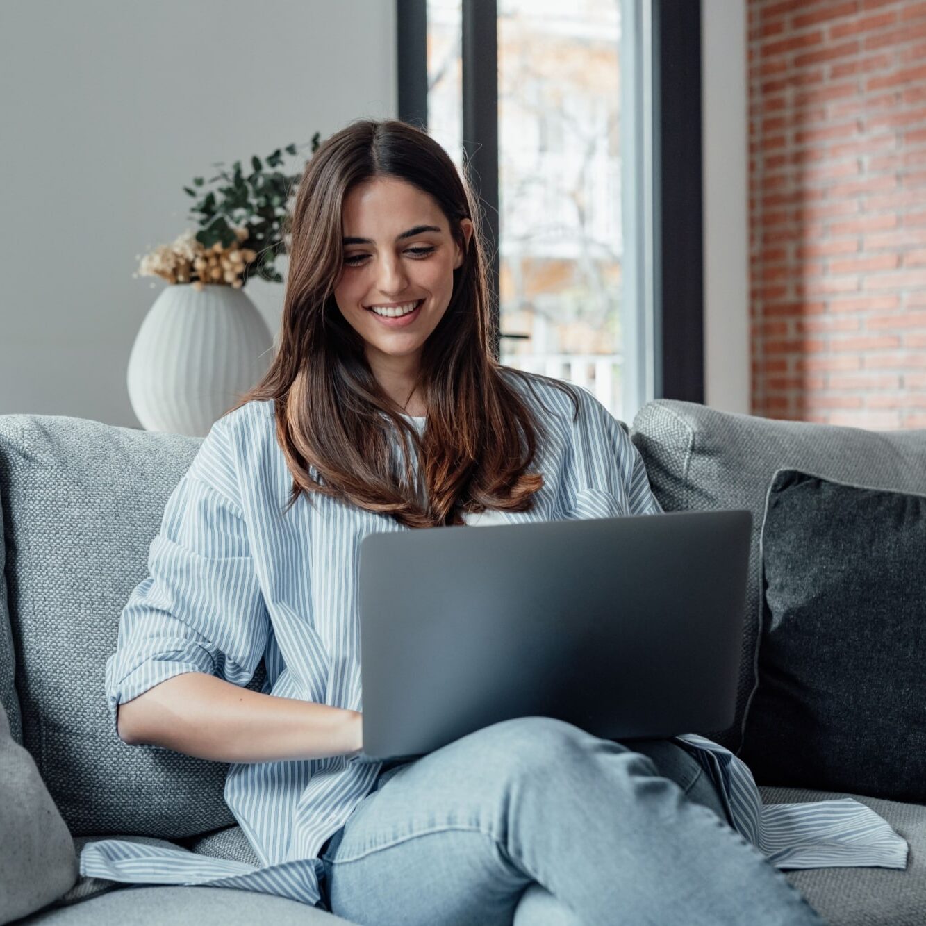 girl sit on couch working on laptop