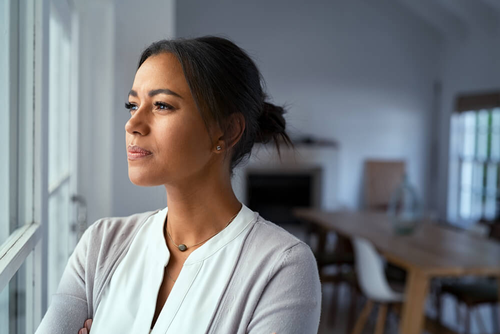 Mature african woman looking outside window