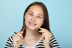 Teenage girl with braces holding gum brush towards mouth