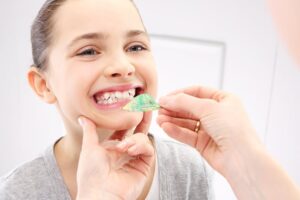 Young girl getting teeth retainers by dental professional