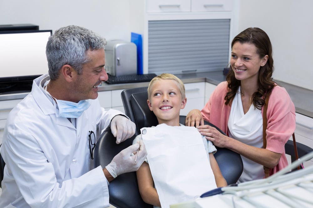 Group photo of mother and son consulting and looking at dental male professional for guidance