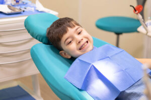 Young toddler sitting in a dental chair smiling with teeth