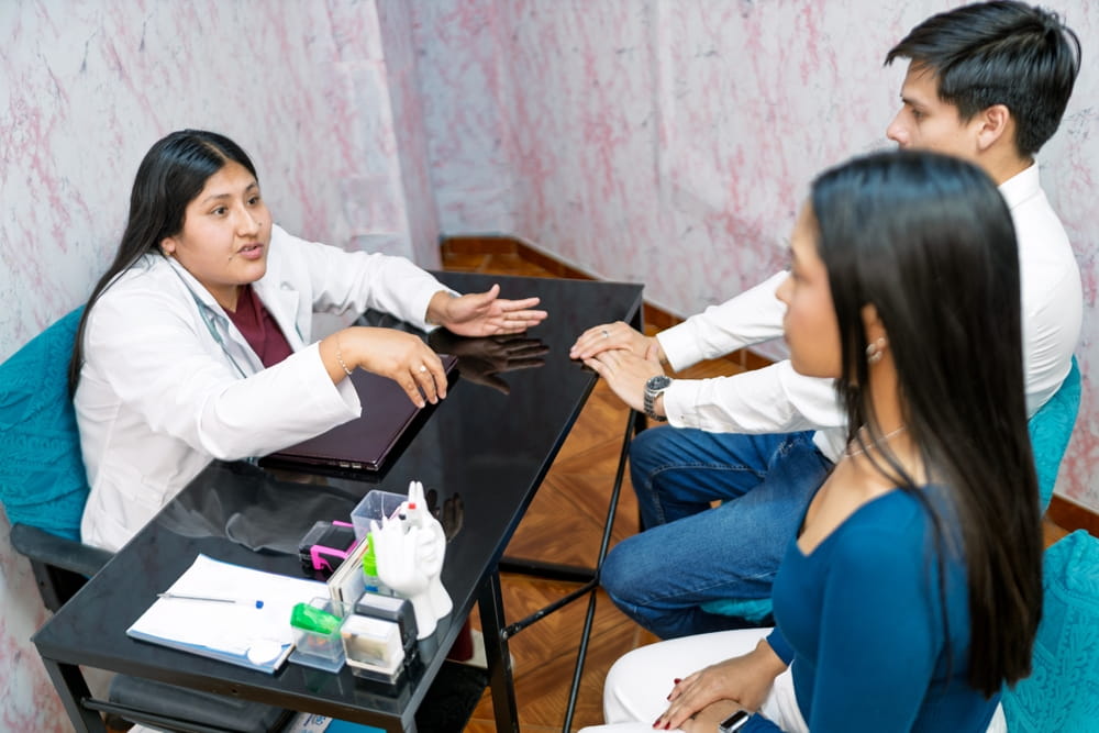Female doctor discussing sexual and reproductive health with a young couple in a medical office