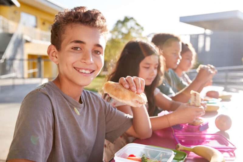 Boy at elementary school lunch table smiling to camera