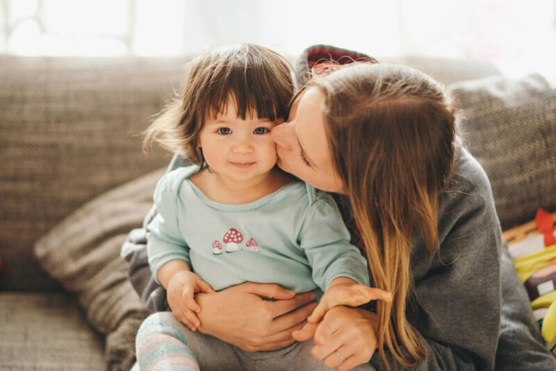 Beautiful young mother with adorable little daughter kissing