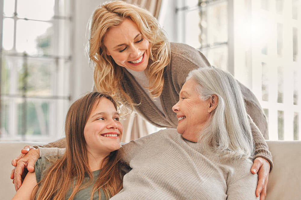 happy family of women on sofa in living room smiling