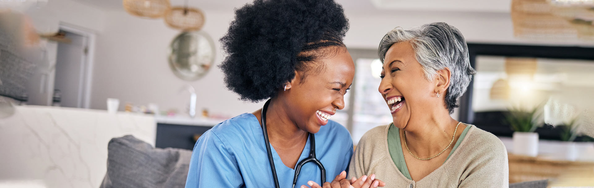 Happy caregiver with an old woman in her home