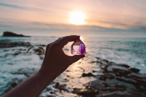 hand holding crystal tower on beach during sunset