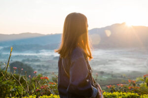 Young woman watching sunrise high in the mountain