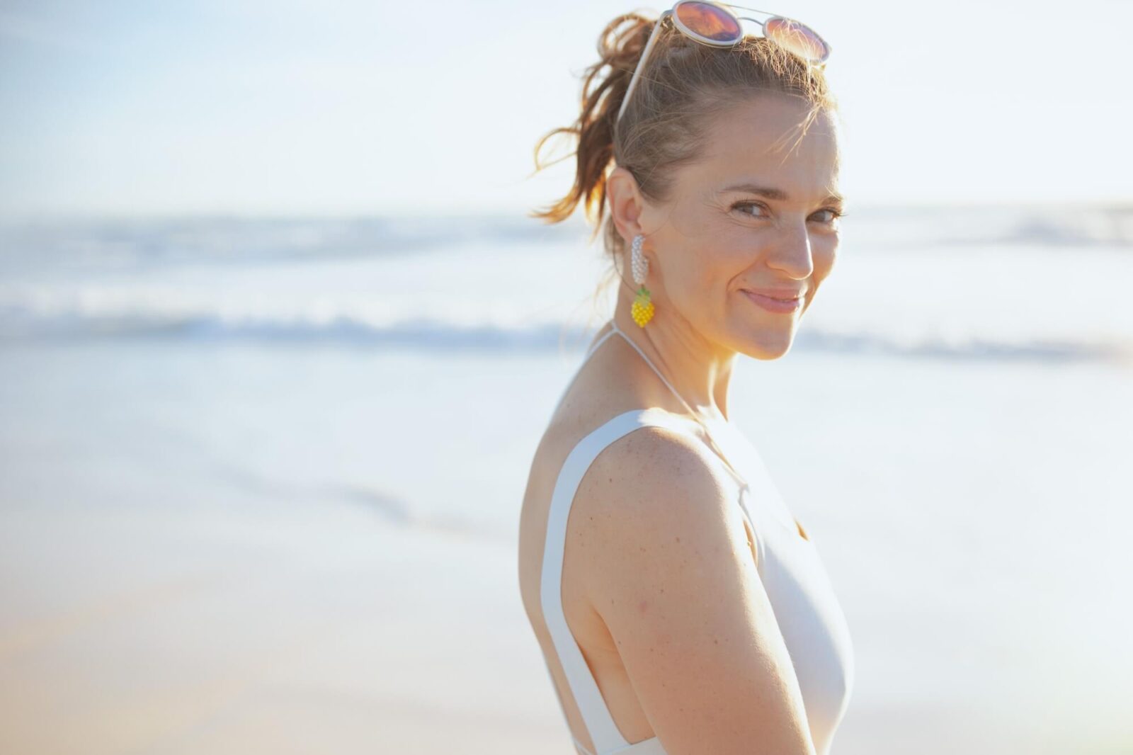 smiling modern middle aged woman in white beachwear at the beach