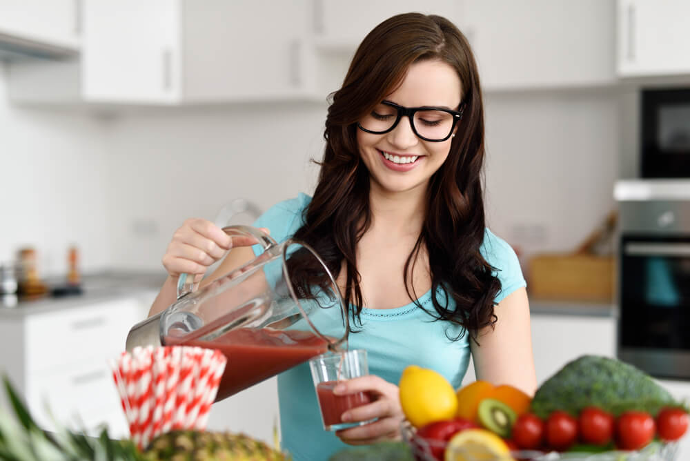 Woman wearing glasses pouring vegetable smoothies