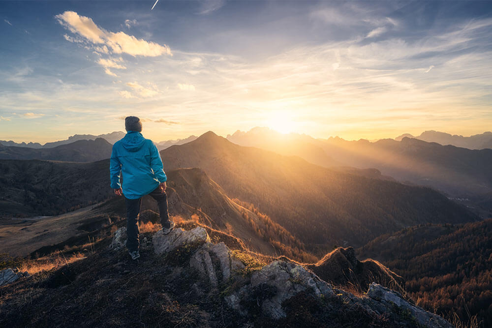 Man on stone on the hill and beautiful mountain valley