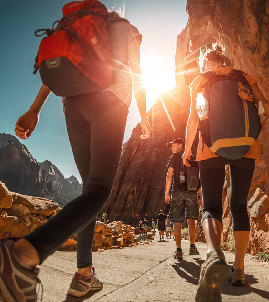 Hikers with backpacks walk on the trail in canyon